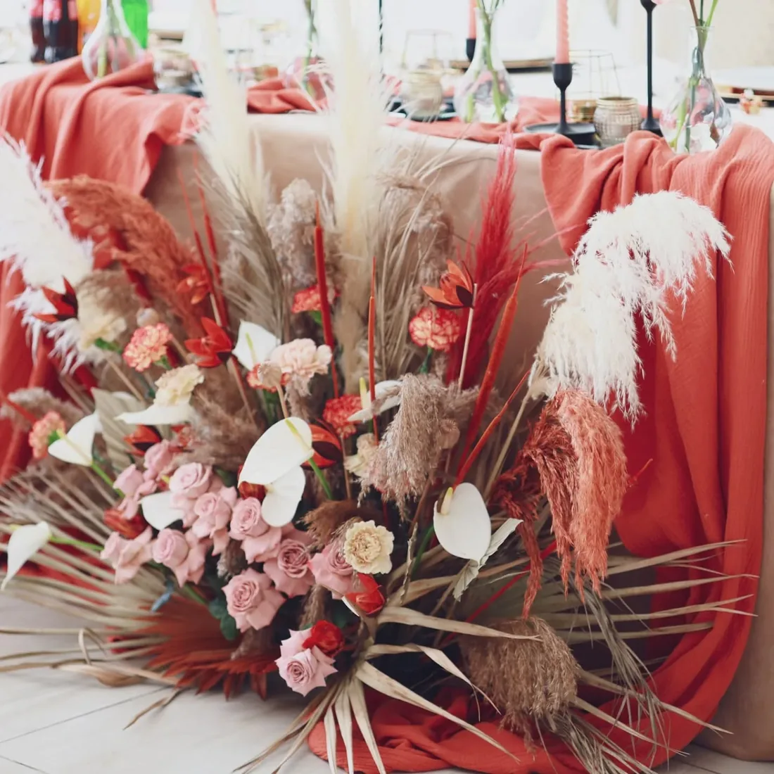 Dekoracja eventowa w stylu boho: suszone trawy i terakotowe tkaniny